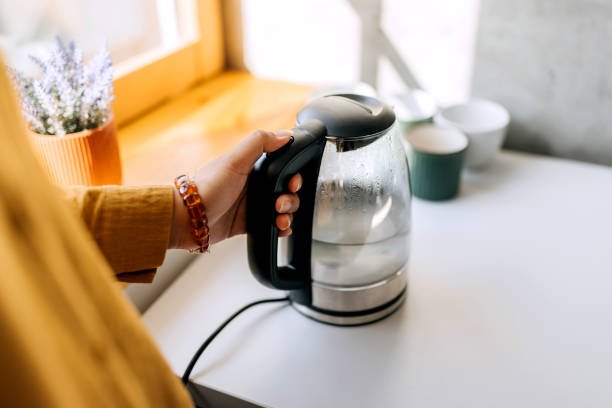 Close up shot of an unrecognisable woman using kettle in kitchen